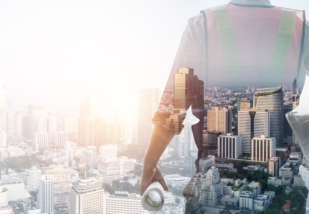 Double exposure of a cityscape and a construction worker holding a blueprint, symbolizing urban development and planning.
