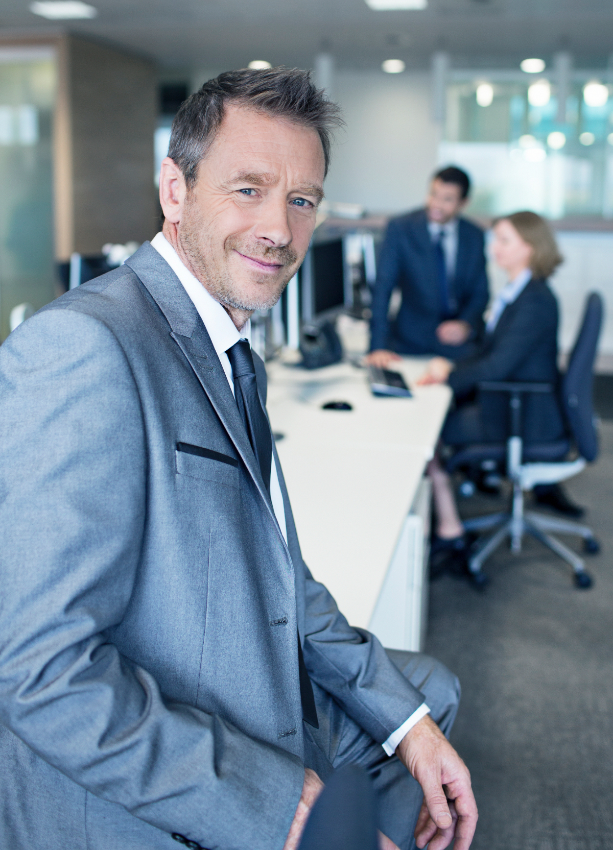 Businessman smiling in. image sits on white desk Businessman smiling in. image sits on white desk