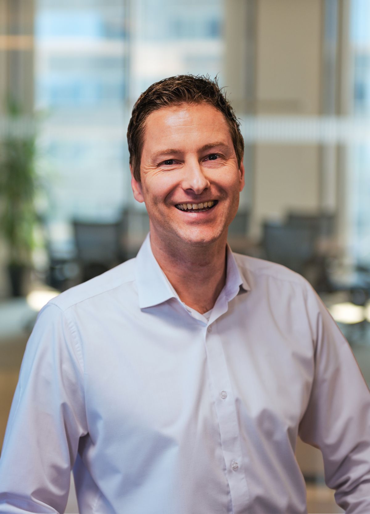 Businessman smiling in. image sits on white desk 